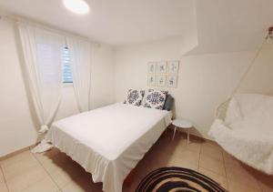 um quarto branco com uma cama e uma janela em Spacious and Peaceful 2BD with a Garden & Parking em Gan H̱ayyim