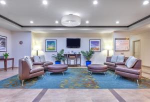 Candlewood Suites Fort Worth West, an IHG Hotel في فورت وورث: غرفة انتظار مع كنب وتلفزيون بشاشة مسطحة
