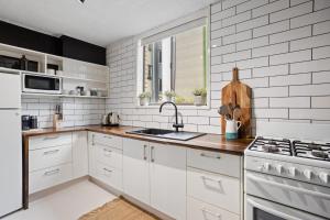a kitchen with white cabinets and a sink and a window at Inner City apartment living in quiet location in Brisbane