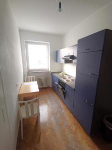 a kitchen with blue cabinets and a table and a window at 2 Room Apartment 15min to Fair in Hannover