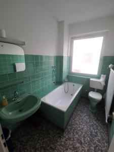 a green and white bathroom with a tub and a toilet at 2 Room Apartment 15min to Fair in Hannover