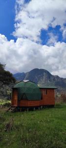 un pequeño edificio con techo verde en un campo en Colombia Mountain Tours Glamping and Cabanas, en Choachí