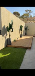 un patio con 2 piante in vaso e una terrazza in legno di וילת צאלים a Yeroẖam