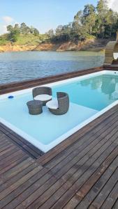 a pool with two chairs and a table on a deck at Atma Eco Village in Guatapé