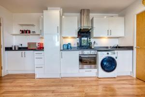 cocina con armarios blancos y lavadora en Wella House Monthly Stays with Parking, en Basingstoke
