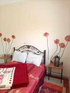 a bedroom with a bed with red sheets and flowers on the wall at Maison du Fleurs in Taroudant