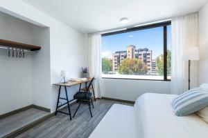 1 dormitorio con cama, escritorio y ventana en Suite 4 - 1 Parque 93, Bogotá, en Bogotá