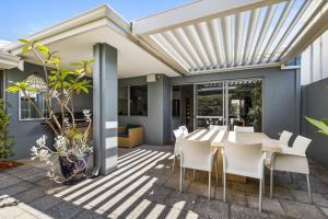 a patio with a white pergola and a table and chairs at Family Comfort - Walk to Beaches, Train and Coffee in Fremantle