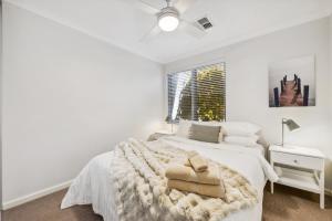 a white bedroom with a bed and a window at Family Comfort - Walk to Beaches, Train and Coffee in Fremantle
