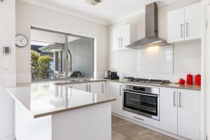 a white kitchen with a sink and a stove at Family Comfort - Walk to Beaches, Train and Coffee in Fremantle