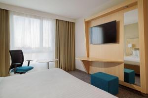 a hotel room with a bed and a tv at Courtyard by Marriott Paris La Defense West - Colombes in Colombes