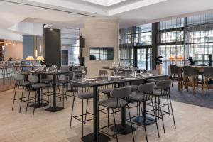 a dining room with tables and chairs and windows at Courtyard by Marriott Paris La Defense West - Colombes in Colombes