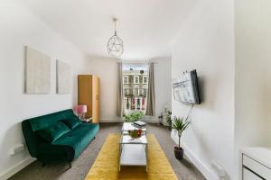 a living room with a green couch and a tv at Spacious Maida Vale 2 Bed Apartment in London