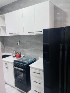 a kitchen with a black refrigerator and white cabinets at WHITEFIELD LUXURY APARTMENT in Orimedu