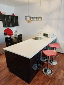 une cuisine avec un comptoir blanc et deux tabourets rouges dans l'établissement Stylish Apartment On Pedestrian Street Randers, à Randers