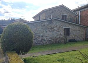 une ancienne maison en pierre avec un bush devant elle dans l'établissement CASA GALLARDO, à Ribadeo