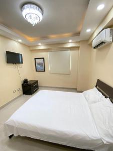 1 dormitorio con cama blanca grande y pantalla en beautiful penthouse Santo Domingo, en Santo Domingo