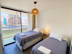 a bedroom with two beds and a large window at Edificio Royal Marine in Iquique