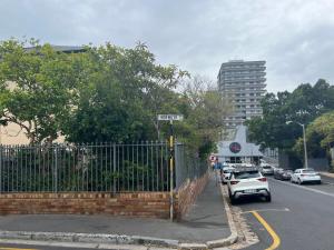 a street with a fence and a parking lot with cars at Sea Point at Princeton Place in Cape Town