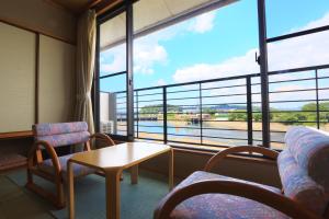 um quarto com uma mesa e cadeiras e uma grande janela em 南郷温泉　二葉屋 em Otsu