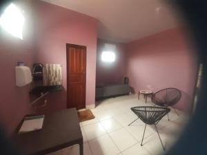 ein Wohnzimmer mit rosa Wänden, einem Tisch und Stühlen in der Unterkunft POUSADA DO PORTAL in Rio Branco