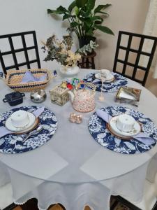 uma mesa branca com pratos e cadeiras azuis e brancos em Charmoso Apartamento Retrô no Hotel Quitandinha com vaga de garagem em Petrópolis
