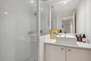 a white bathroom with a shower and a sink at Central Fremantle 2 Bedroom - Walk to Shops and Beach in Fremantle +16 photos