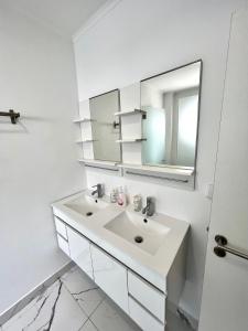 a white bathroom with a sink and a mirror at Oeiras Beach guest house in Oeiras