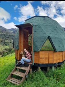 a person sitting in a small house with a dog at Colombia Mountain Tours Glamping and Cabanas in Choachí