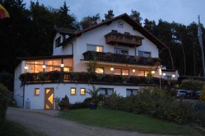 Großes weißes Haus mit Balkon und Beleuchtung in der Unterkunft Landhotel Waldesruh in Furth im Wald