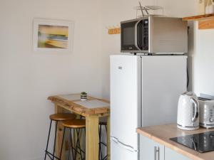 a kitchen with a refrigerator and a table with a microwave at Half Pint - Uk46614 in Tain