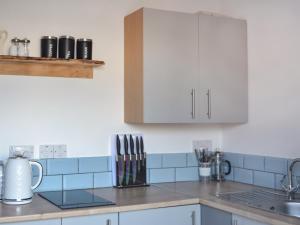 a kitchen with white cabinets and blue tiles at Half Pint - Uk46614 in Tain