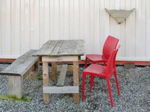 une table en bois et deux chaises rouges à côté d'un banc dans l'établissement Half Pint - Uk46614, à Tain