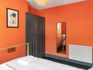 ein Schlafzimmer mit einer orangefarbenen Wand mit einem Bett und einem Spiegel in der Unterkunft Eaton Beach House in Margate