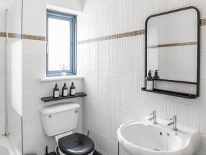 a white bathroom with a toilet and a sink at Eaton Beach House in Margate