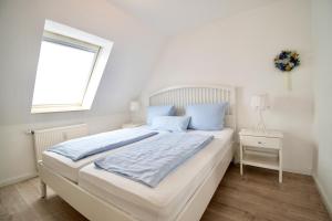een witte slaapkamer met een groot bed en een raam bij Villa Wilhelma Apartment A2 1 OG in Timmendorfer Strand