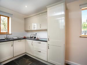 a kitchen with white cabinets and a window at Curlew in Hemborough Post