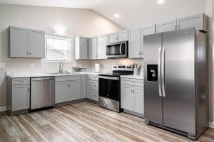 uma cozinha com armários brancos e um frigorífico de aço inoxidável em Essential Escape em Radcliff