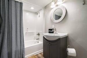 uma casa de banho com um lavatório, uma banheira e um espelho. em Essential Escape em Radcliff