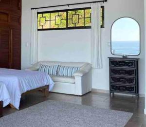 a bedroom with a couch and a window and a mirror at Villa Del Mar 2 Spectacular ocean view! in Dominical