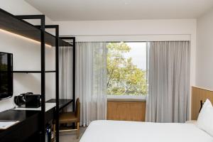 a bedroom with a bed and a desk and a window at Quay Perth in Perth