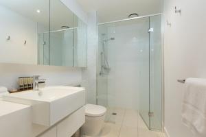 a white bathroom with a sink and a shower at The Sebel Melbourne Docklands Hotel in Melbourne