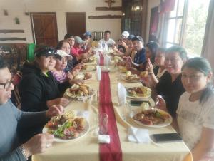 Un groupe de personnes assises à une longue table qui mange de la nourriture dans l'établissement Sama Jauka, à Guano