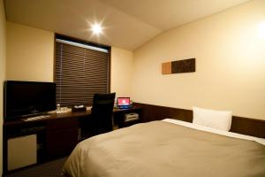 Ochanomizu Hotel Shoryukan في طوكيو: غرفة في الفندق بها سرير ومكتب وبه جهاز كمبيوتر