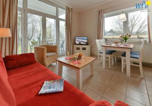 a living room with a red couch and a table at Haus am Hövt - Ferienwohnung 2 in Göhren +32 photos