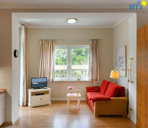 a living room with a red couch and a window at Haus am Hövt - Ferienwohnung 1 in Göhren