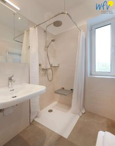 a white bathroom with a shower and a sink at Haus am Hövt - Ferienwohnung 1 in Göhren +25 photos