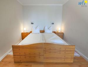 a bedroom with a large wooden bed with white sheets at Haus am Hövt - Ferienwohnung 10 in Göhren