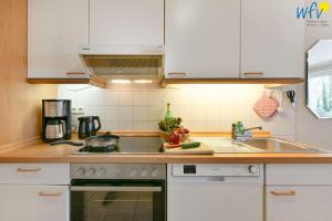 a kitchen with white cabinets and a sink at Haus am Hövt - Ferienwohnung 10 in Göhren