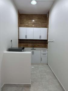 una cocina con armarios blancos y fregadero en وحدة سكنية مع كراج خاص للسيارة, en Bīshat Mushayţ